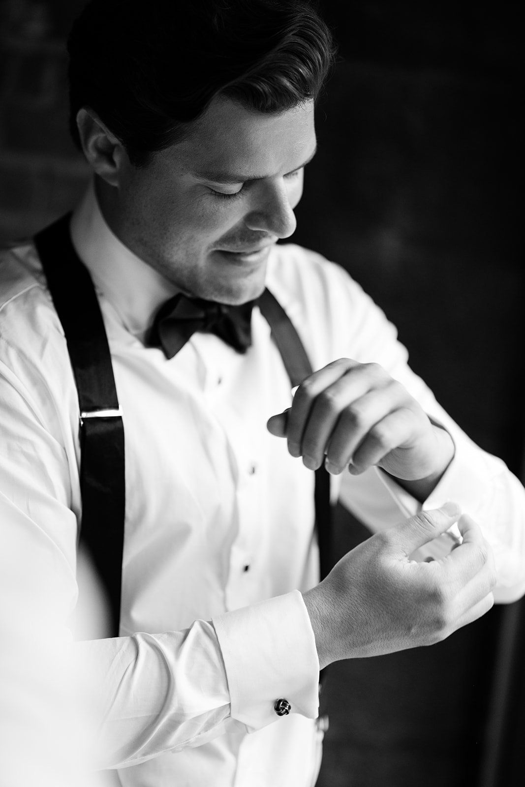Groom fastening his cufflinks in the dark of the Boiler Room at City Winery Hudson Valley, black and white